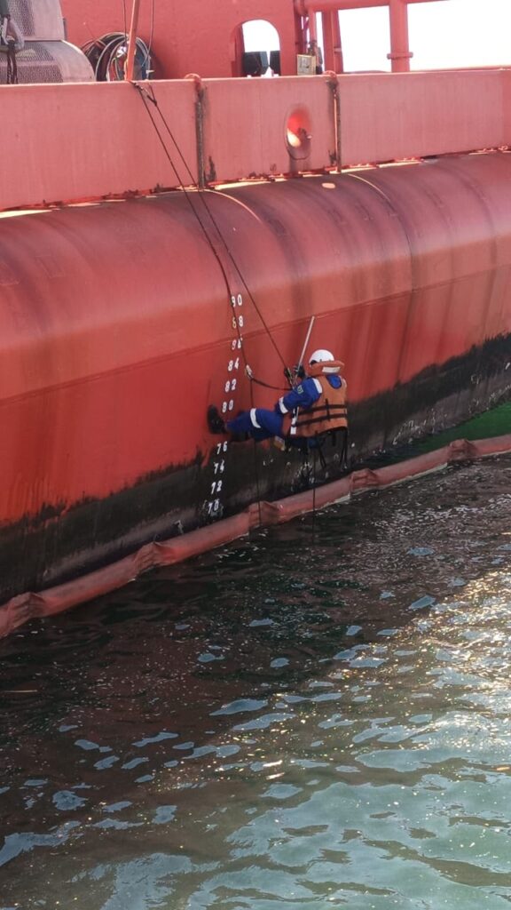 T&eacute;cnico em acesso por corda intervindo no costado do navio junto &agrave;s marcas de calado